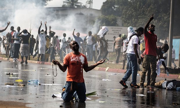 A supporter of the Gabonese opposition leader Jean Ping kneels in front of security forces after the disputed election result. Photograph: Marco Longari/AFP/Getty