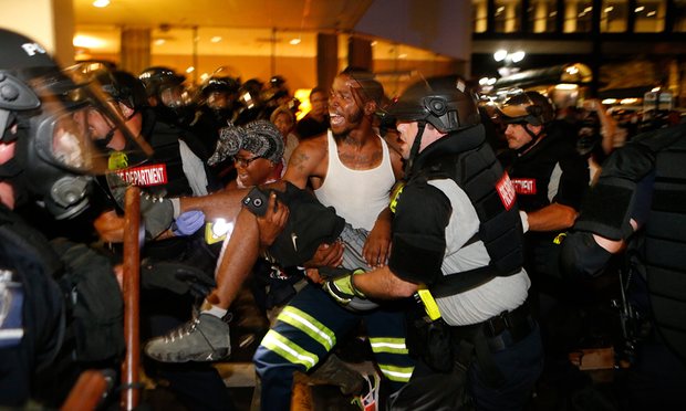 Police and protesters carry a seriously wounded protester into the parking area of the the Omni Hotel during a march to protest the death of Keith Scott. Photograph: Brian Blanco/Getty Images