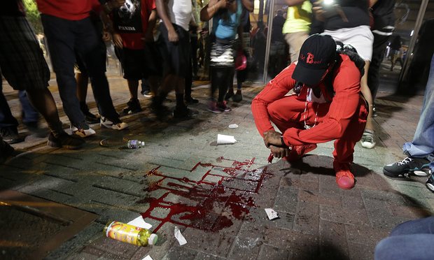 A man squats near a pool of blood after a man was injured during a protest of Tuesday’s fatal police shooting of Keith Lamont Scott in Charlotte. Photograph: Chuck Burton/AP