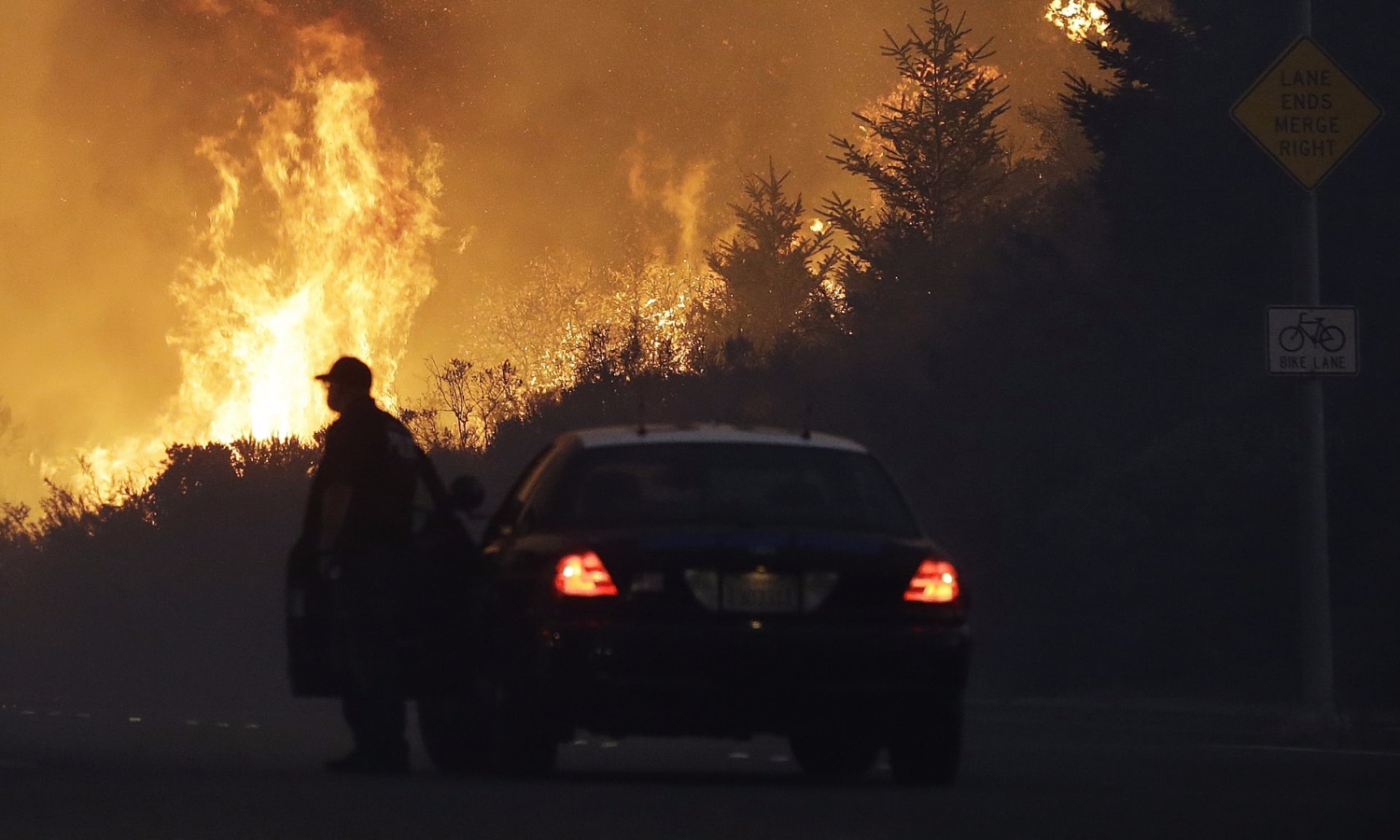A law enforcement officer blocks a road as flames burn in a residential area in Santa Rosa, California. Photograph: Jeff Chiu/AP