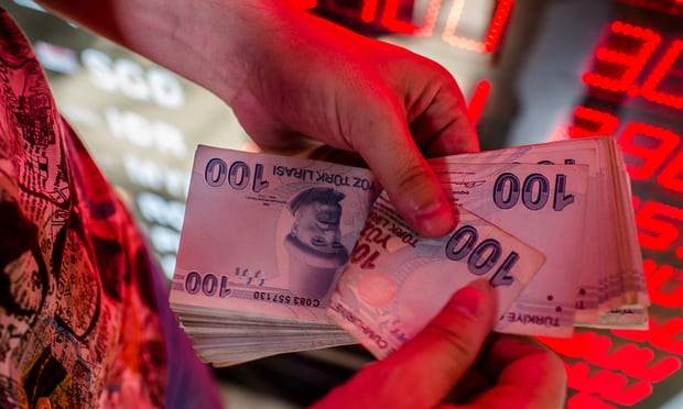 A money changer counts Turkish lira at an exchange office in Istanbul. It has fallen 40% this year. Photograph: Yasin Akgul/AFP/Getty Images