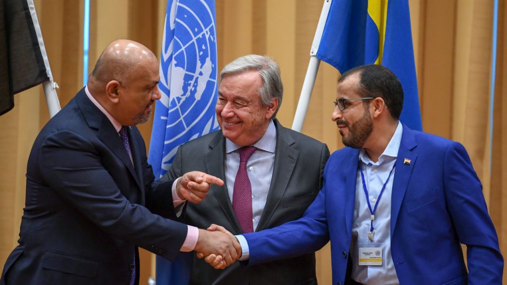 Jonathan Nackstrand, AFP | Yemen's Foreign Minister Khaled al-Yamani (L) and rebel negotiator Mohammed Abdelsalam (R) shake hands under the eyes of UN Secretary General Antonio Guterres (C) during peace consultations in Sweden