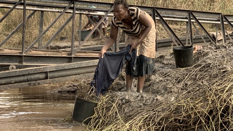 A woman washes clothing in the dirty waters of the Buzi River near Beira, Mozambique. (Stephanie Jenzer/CBC News)