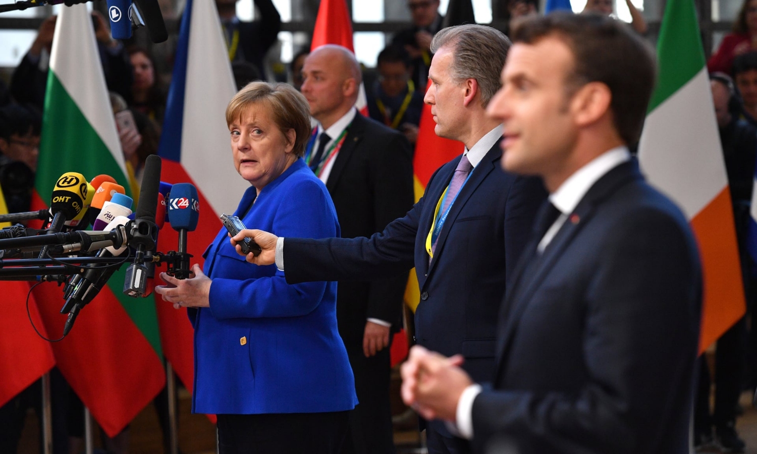 The German chancellor, Angela Merkel, looking at the French president, Emmanuel Macron, as they both conduct media interviews on arrival at the summit. Photograph: Leon Neal/Getty Images