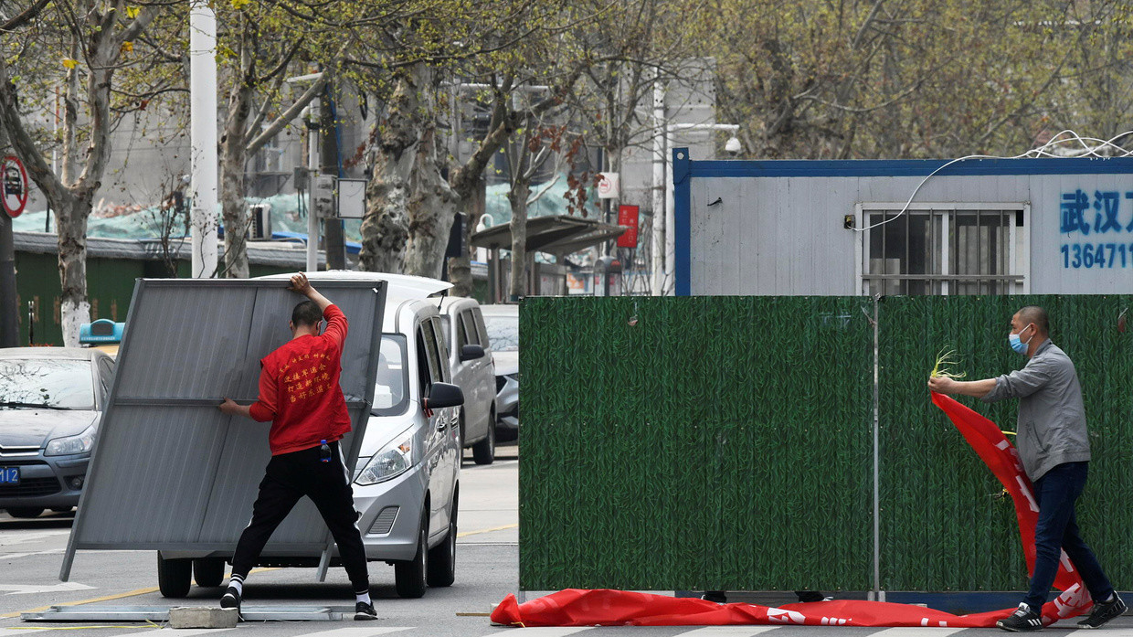 Workers wearing face masks remove barriers on a street in Wuhan, the epicenter of the novel coronavirus outbreak, as the city has started to loosen its lockdown, in Hubei province, China, March 21, 2020. ©  Reuters / China Daily