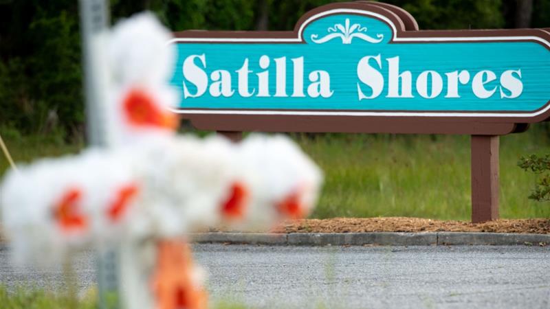 A cross with flowers and a letter "A" sits at the entrance to the Satilla Shores neighbourhood where Ahmaud Arbery was shot and killed [Sean Rayford/Getty Images/AFP]