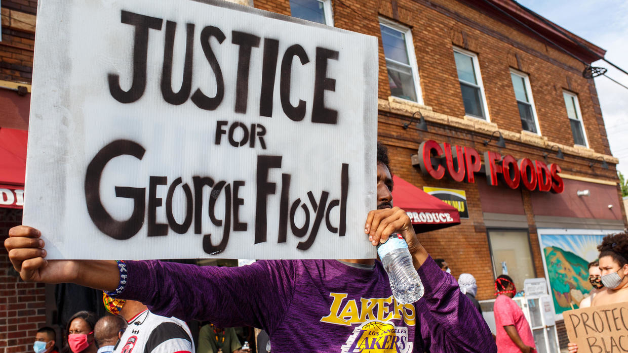 A man holds a sign while protesting near the area where video was filmed of a Minneapolis officer kneeling on the neck of George Floyd, a black man who died on May 25, 2020. © Kerem Yucel, AFP