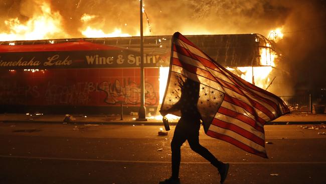 A protester carries a US flag upside down. Picture: Julio Cortez/APSource:AP
