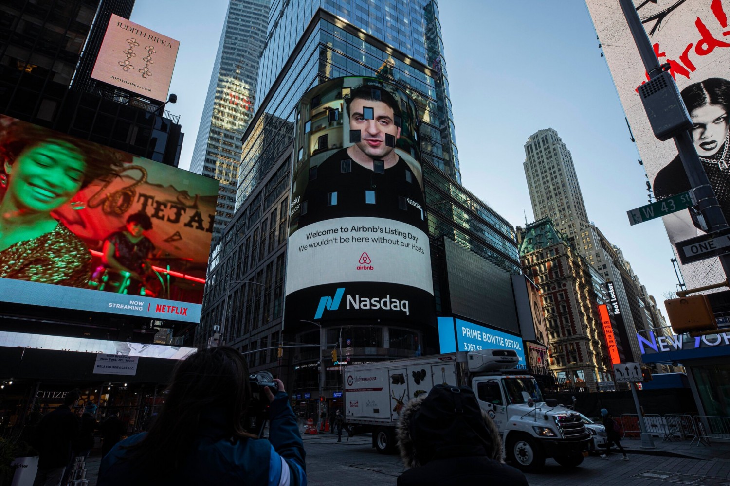 Brian Chesky, Airbnb’s chief executive,  on Nasdaq’s digital billboard in Times Square on Thursday.Credit...Hiroko Masuike/The New York Times