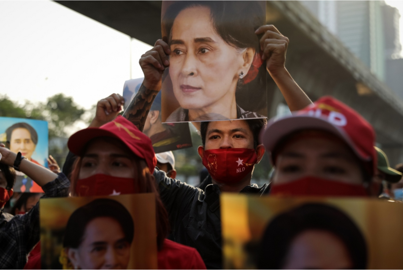 People hold up images of Myanmar's de facto leader Aung San Suu Kyi at a protest outside Myanmar's embassy in Thailand. | Lauren DeCicca/Getty Images