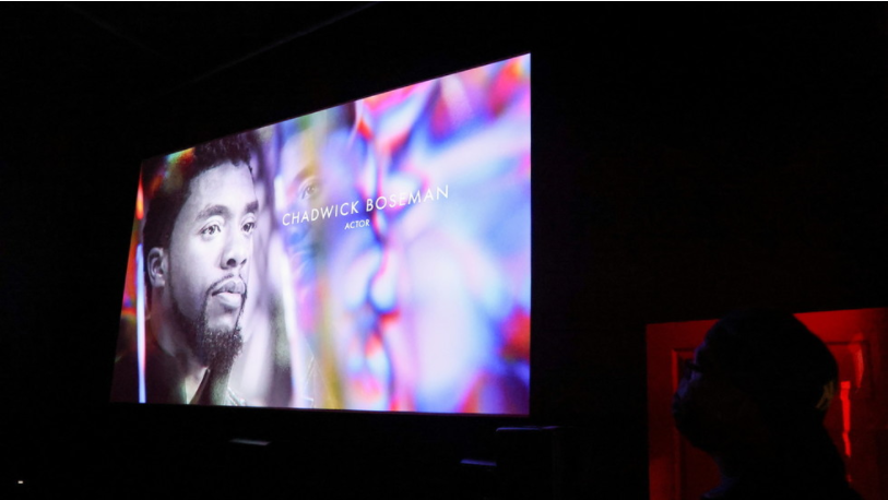 An audience member watches as Chadwick Boseman appears on screen during the annual In Memoriam presentation, at an Oscars watch party at the Stuart & Cinema Cafe, in Brooklyn, New York, U.S., April 25, 2021. © REUTERS/Caitlin Ochs