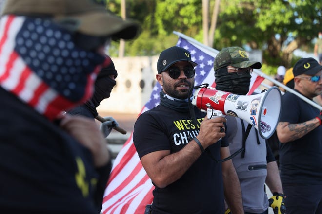 Enrique Tarrio (C), leader of the Proud Boys, uses a megaphone to address people gathered at the Torch of Friendship to remember the one year anniversary of the killing of George Floyd on May 25, 2021 in Miami, Florida.