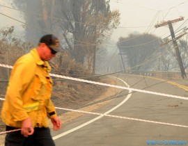 Orange County firefighter Robert Bucho tapes off Highway 150 near Santa Paula for caution as power lines brought down by the Thomas Fire block the road. The road is closed until further notice.