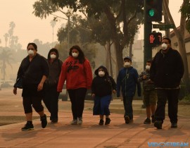 A family wears face masks as they walk through the smoke filled streets after the Thomas wildfire swept through Ventura, Calif. on Dec. 6, 2017. California motorists commuted past a blazing inferno Wednesday as wind-whipped wildfires raged across the