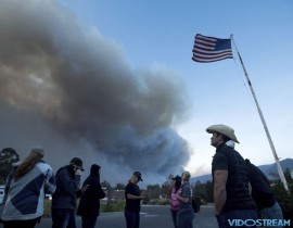 A group of horse rescuers stages in a parking lot as smoke from the Thomas fire billows over Ojai, Calif., on Dec. 7, 2017. The volunteers, who met through a Facebook group, estimated that they have evacuated more than 100 horses from the fire.