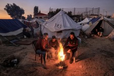 Men warm up around a fire on Dec. 18 outside one of the tents housing displaced Palestinians in Rafah. Mahmud Hams / AFP - Getty Images