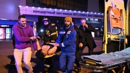 An injured woman is transported to an ambulance near the Crocus City Hall concert venue following a reported shooting incident, near Moscow, Russia. ©  Sputnik/Sergey Bobylev
