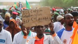 Nigeriens gather in a street to protest against the US military presence in Niamey, Niger on April 13, 2024. The sign reads "This is not Washington, it's Agadez." © Mahamadou Hamidou, Reuters