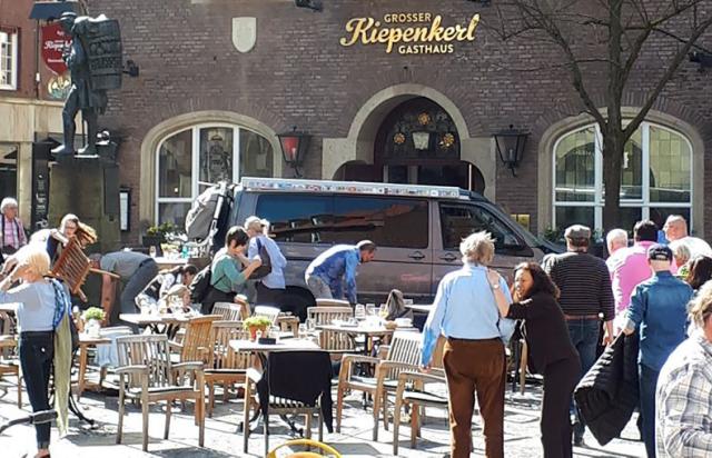 People stay in front of a restaurant in Muenster, Germany, Saturday, April 7, 2018 after a vehicle crashed into a crowd killing four people and injuring 20 others. The German news agency dpa has quoted police as saying the driver of that car in Muenster h