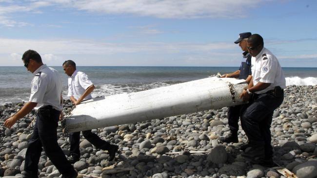 Authorities carry a barnacle-encrusted flaperon that washed up on the French Island of Reunion in 2015. It is one of only three pieces of debris, all wing parts washed up on Indian Ocean Coasts confirmed as coming from MH370. Picture: EPASource: