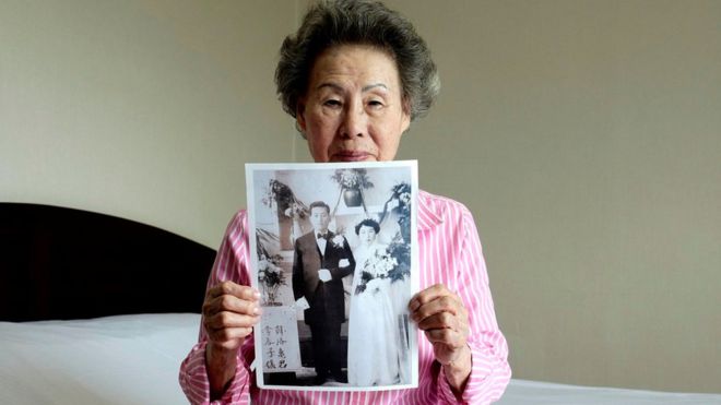 EPA / Lee Chun-ja shows a picture of her wedding which she intends to give to her relatives in North Korea