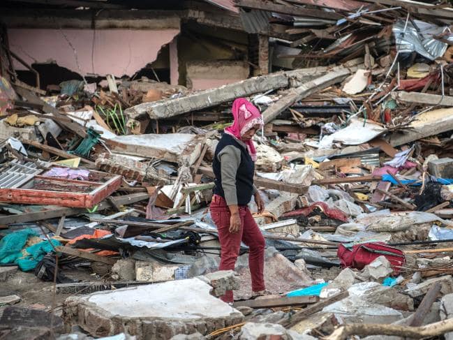 A woman looks through the rubble of a building that was destroyed by the tsunami.Source:Getty Images