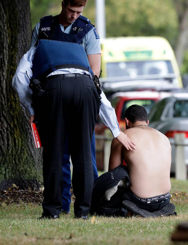 Police console a man outside a mosque in central Christchurch.
