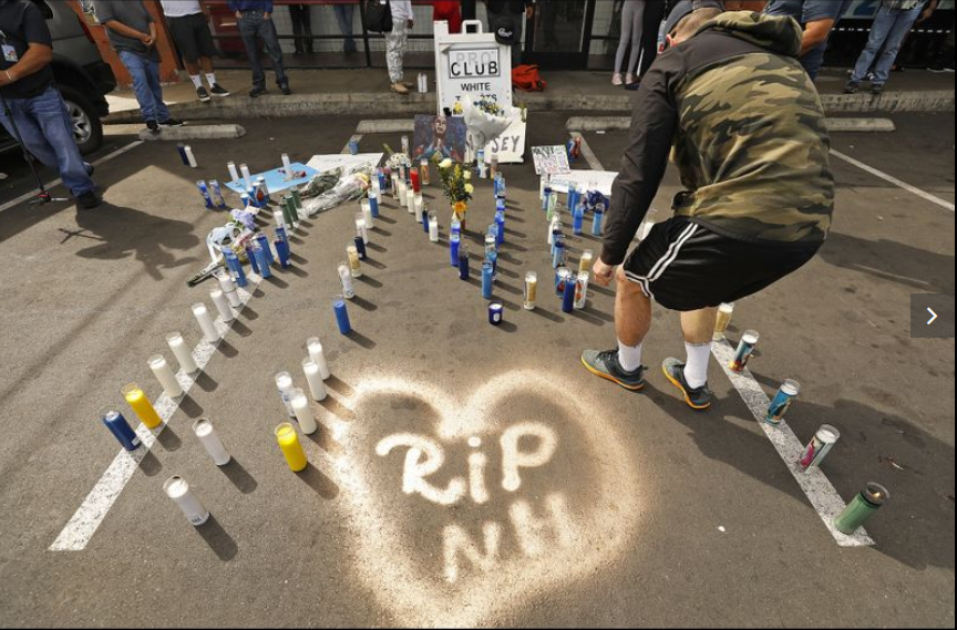Jesse Junco, 28, from San Bernardino lights candles Monday morning at one of a few growing memorials in front of the Marathon Clothing store. (Al Seib / Los Angeles Times)