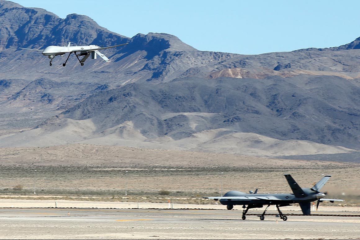 An MQ-1B Predator remotely piloted aircraft flies past a MQ-9 Reaper RPA as it taxis during a training mission at Creech Air Force Base in Indian Springs, Nevada. | Isaac Brekken/Getty Images