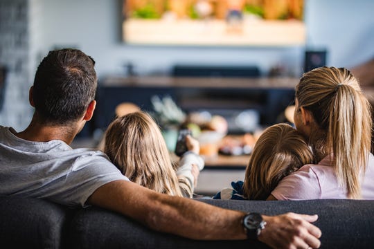 Back view of a relaxed family watching TV on sofa in the living room. (Photo: Getty Images)