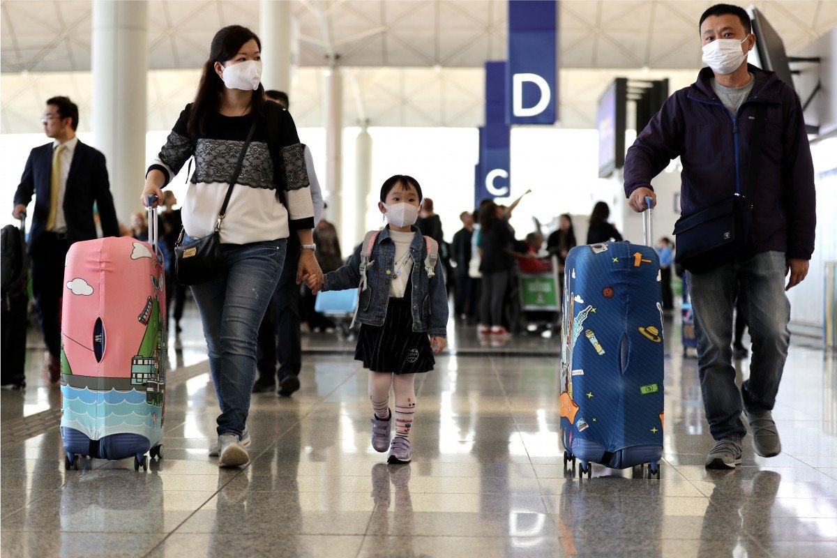 Travellers wearing face masks walk through Hong Kong International Airport on Wednesday as the deadly coronavirus spreads globally. Photo: Bloomberg