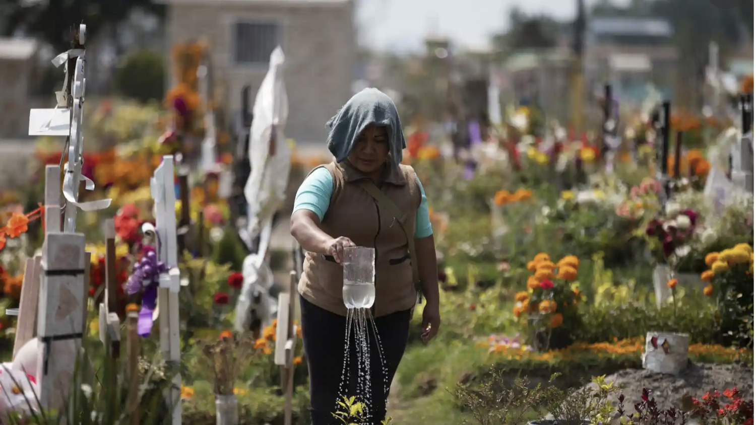 A woman waters her father’s grave at the Valle de Chalco municipal cemetery on the outskirts of Mexico City on Thursday. Photograph: Fernando Llano/AP