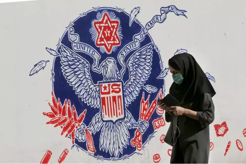This file photo shows an Iranian woman walking past a mural painted on the outer walls of the former U.S. embassy in the Iranian capital Tehran, on November 4, 2020. ATTA KENARE/AFP VIA GETTY IMAGES/GETTY