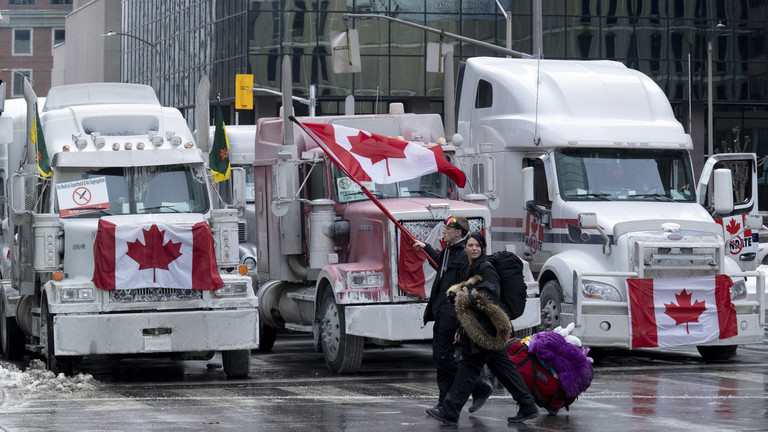 Protesters walk past trucks parked in downtown Ottawa. February 2, 2022. © AP / Adrian Wyld / The Canadian Press