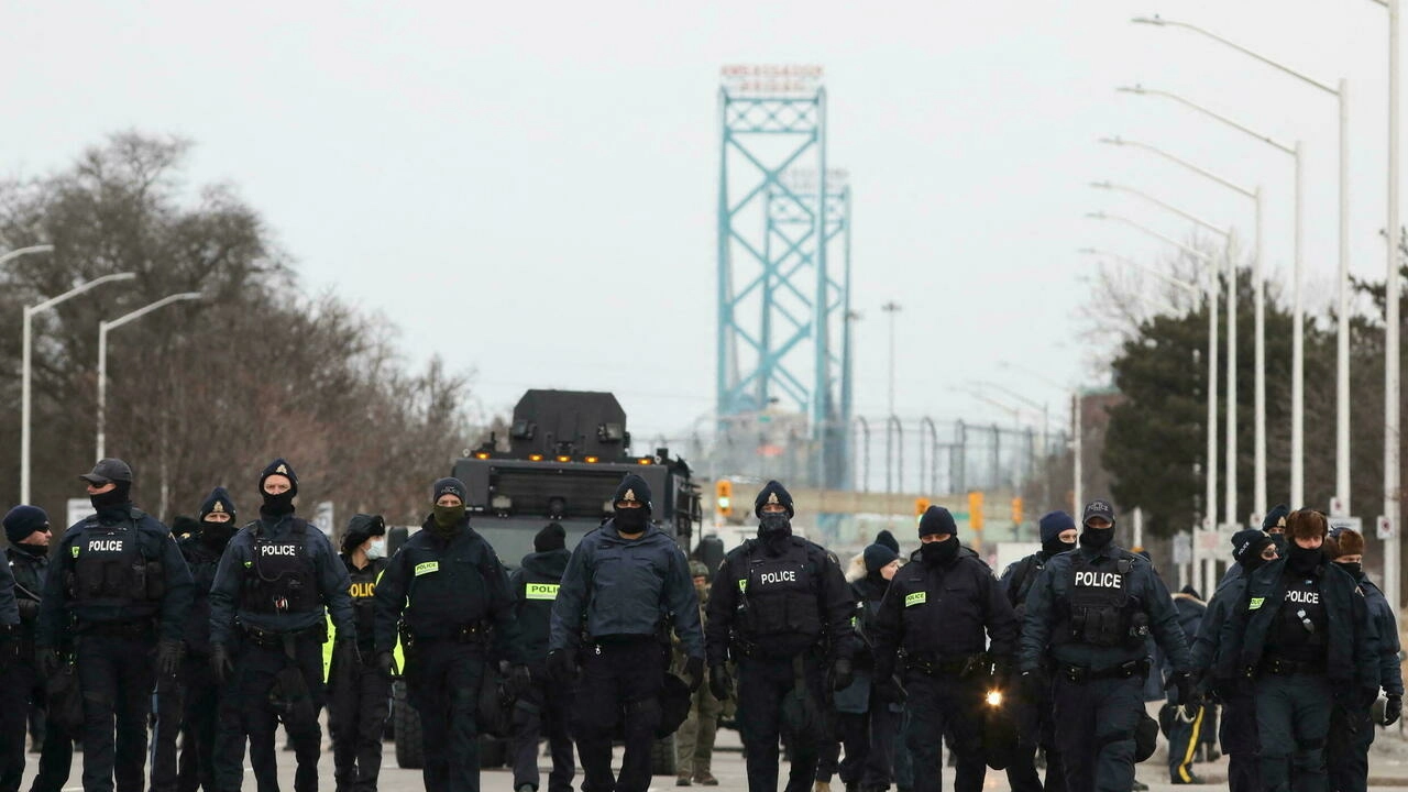 Police officers move along a road leading to the Ambassador Bridge in Windsor, Ontario, Canada on February 13, 2022. © Carlos Osorio, Reuters