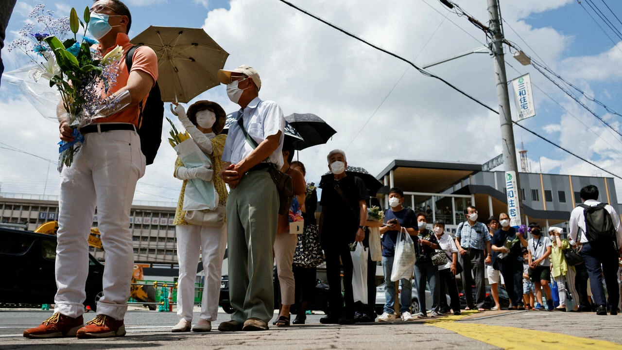 People queue up to offer flowers and pray at the site where former Japanese Prime Minister Shinzo Abe was shot while campaigning for a parliamentary election in Nara, western Japan, on July 9, 2022. © Issei Kato, Reuters