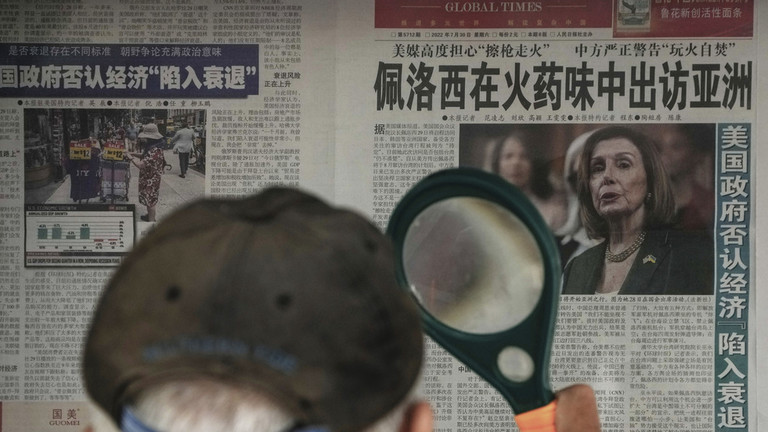 A man uses a magnifying glass to read an article by the Global Times on US House Speaker Nancy Pelosi's Asia visit at a stand in Beijing. © AP / Andy Wong