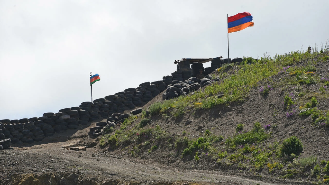 This picture taken near the village of Sotk, Armenia, on June 18, 2021 shows Azerbaijan's flag (L) and Armenia's flag flying at a border check point between the countries. © Karen Minasyan, AFP