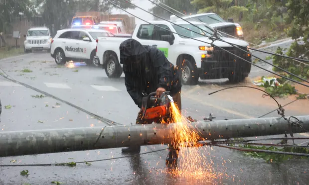 A worker cuts an electricity pole that was downed by Hurricane Fiona as it blocks a road in Cayey, Puerto Rico, on Sunday. Photograph: Stephanie Rojas/AP