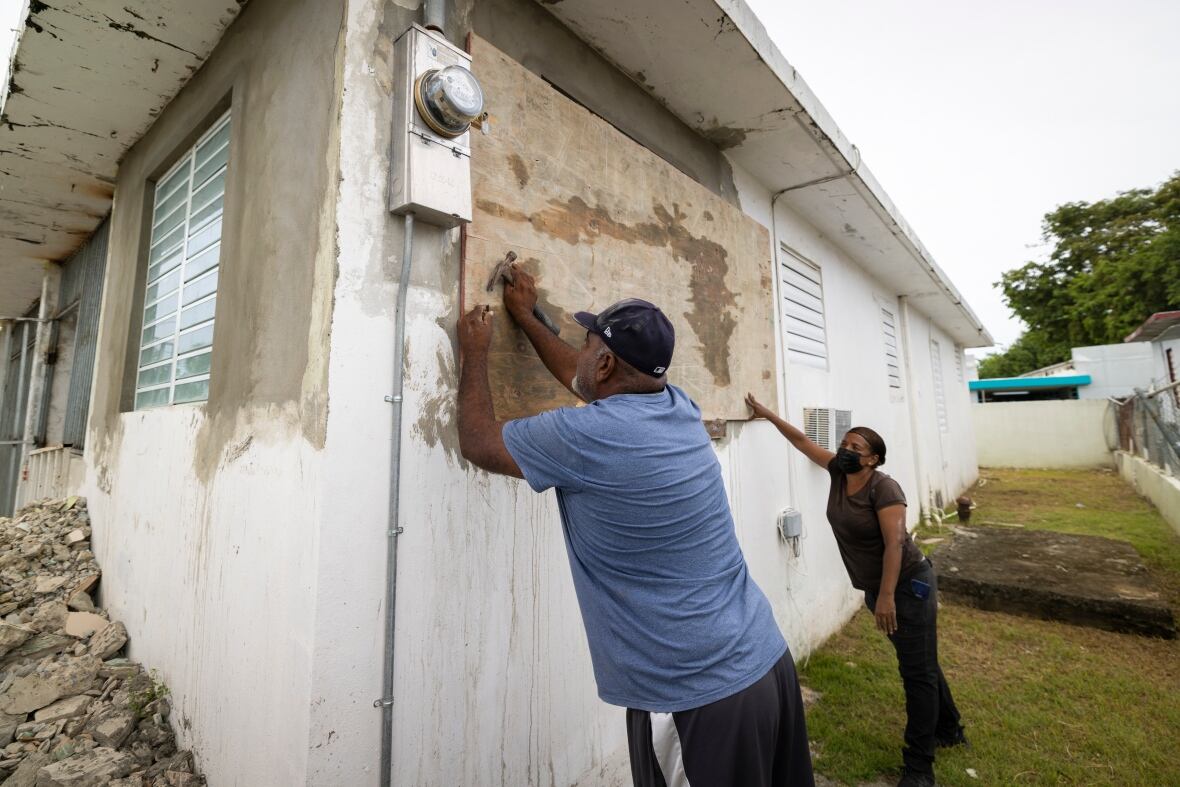 Residents attach protective plywood to a window of their home in preparation for the Fiona's arrival in Loiza, Puerto Rico, on Saturday. (Alejandro Granadillo/The Associated Press)