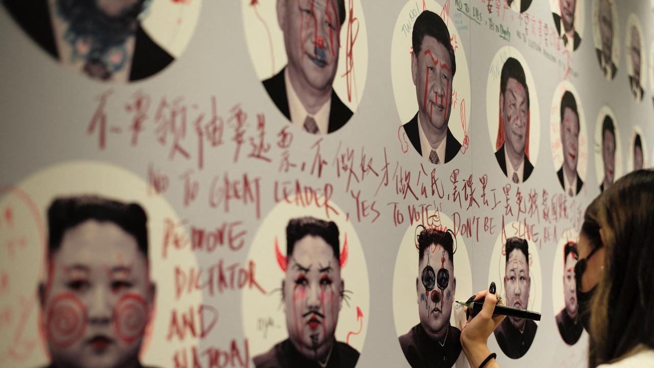 A woman doodles over a portrait of North Korean leader Kim Jong-un on a graffiti wall showing images of various dictators during the Oslo Freedom Forum in Taipei. Picture: Sam Yeh/AFP