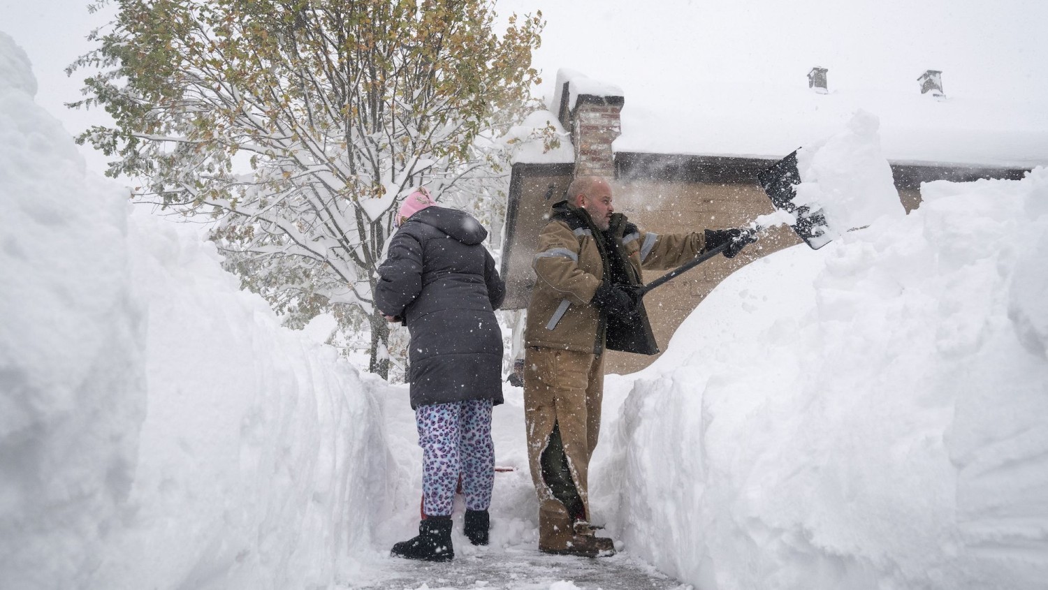 Jenny Vega (L) and Roberto Rentas shovel snow in front of their house in Buffalo Friday. Brendan Bannon/The New York Times/Redux