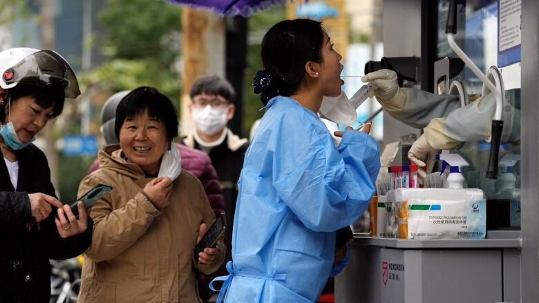 A woman gets swabbed to be tested for COVID-19 at a nucleic acid testing site in Shanghai, on Tuesday. (Aly Song/Reuters)