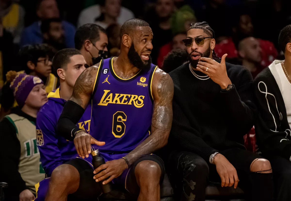 Lakers forward LeBron James chats with injured teammate Anthony Davis on the bench during a game against the Hornets at Crypto.com Arena on Dec. 23.(Gina Ferazzi / Los Angeles Times)