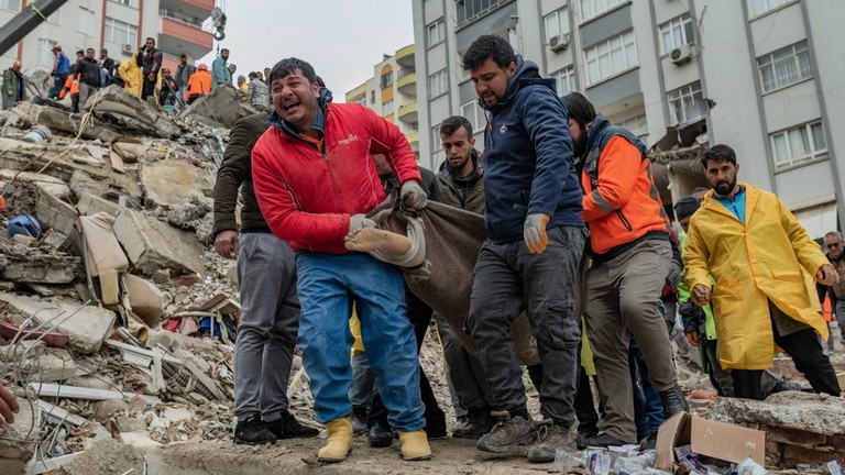 Rescuers carry a body found in the rubble in Adana, Türkiye, February 6, 2023 ©  AFP / Can Erok