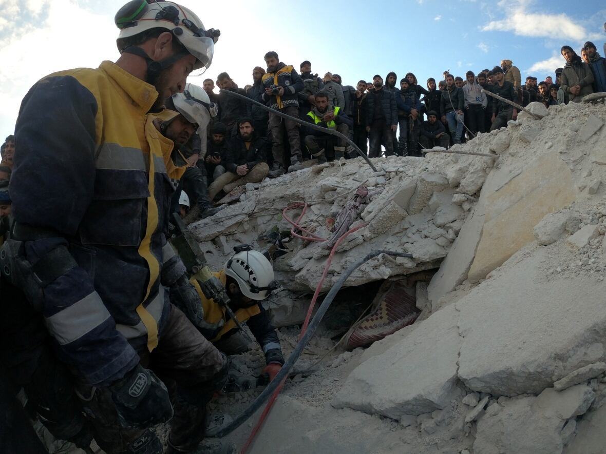 Members of the search and rescue group known as the White Helmets dig through the rubble of a collapsed building in Bisnia, Syria, following powerful earthquakes that rocked the region on Monday. (White Helmets/Reuters)
