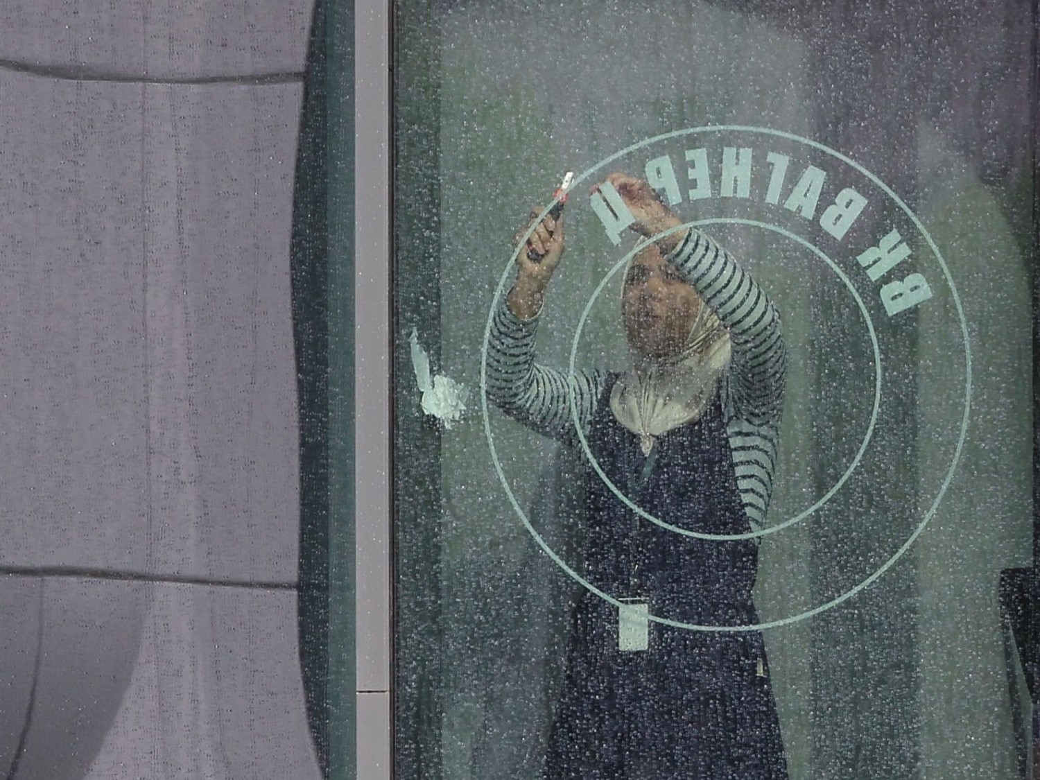 A worker removes the logo on a window of the PMC Wagner Centre in St. Petersburg. ANTON VAGANOV/REUTERS