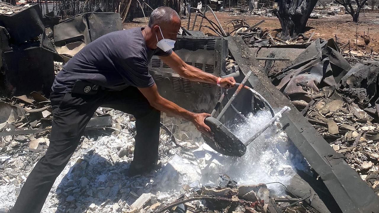 Anthony La Puente, 44, recovers items from his house in the aftermath of a wildfire in Lahaina, western Maui, Hawaii on August 11, 2023. (Photo by Paula RAMON / AFP)
