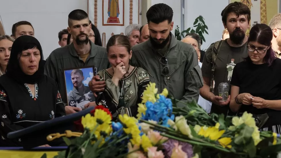 EPA | Mourners at the wake held photos of Andriy Pilshchykov, who served in the 40th tactical aviation brigade