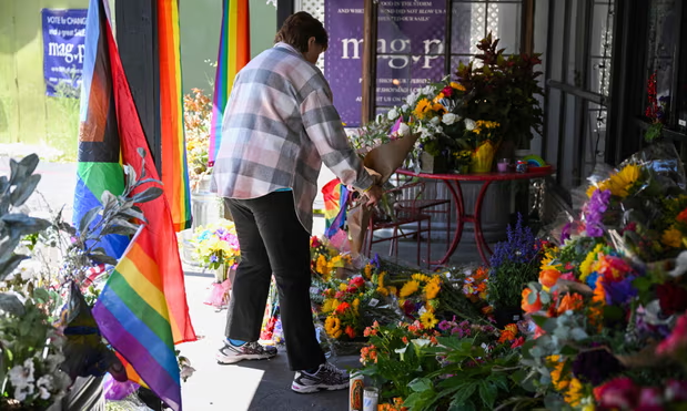 A person leaves flowers at a makeshift memorial outside the Mag.Pi clothing store in Cedar Glen, near Lake Arrowhead, California, on Monday. Photograph: Robyn Beck/AFP/Getty Images